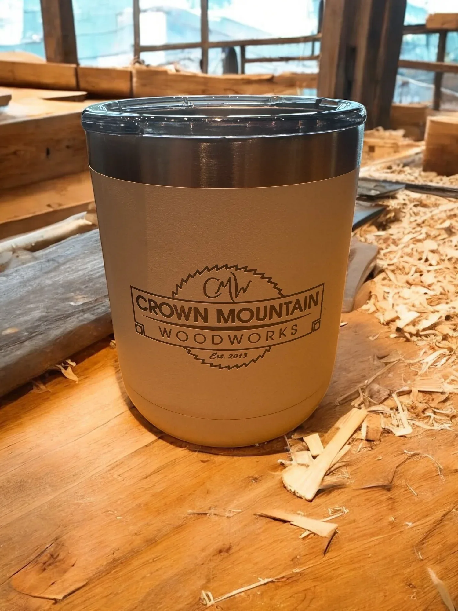 Engraved Crown Mountain Woodworks tumbler on a woodshop bench
